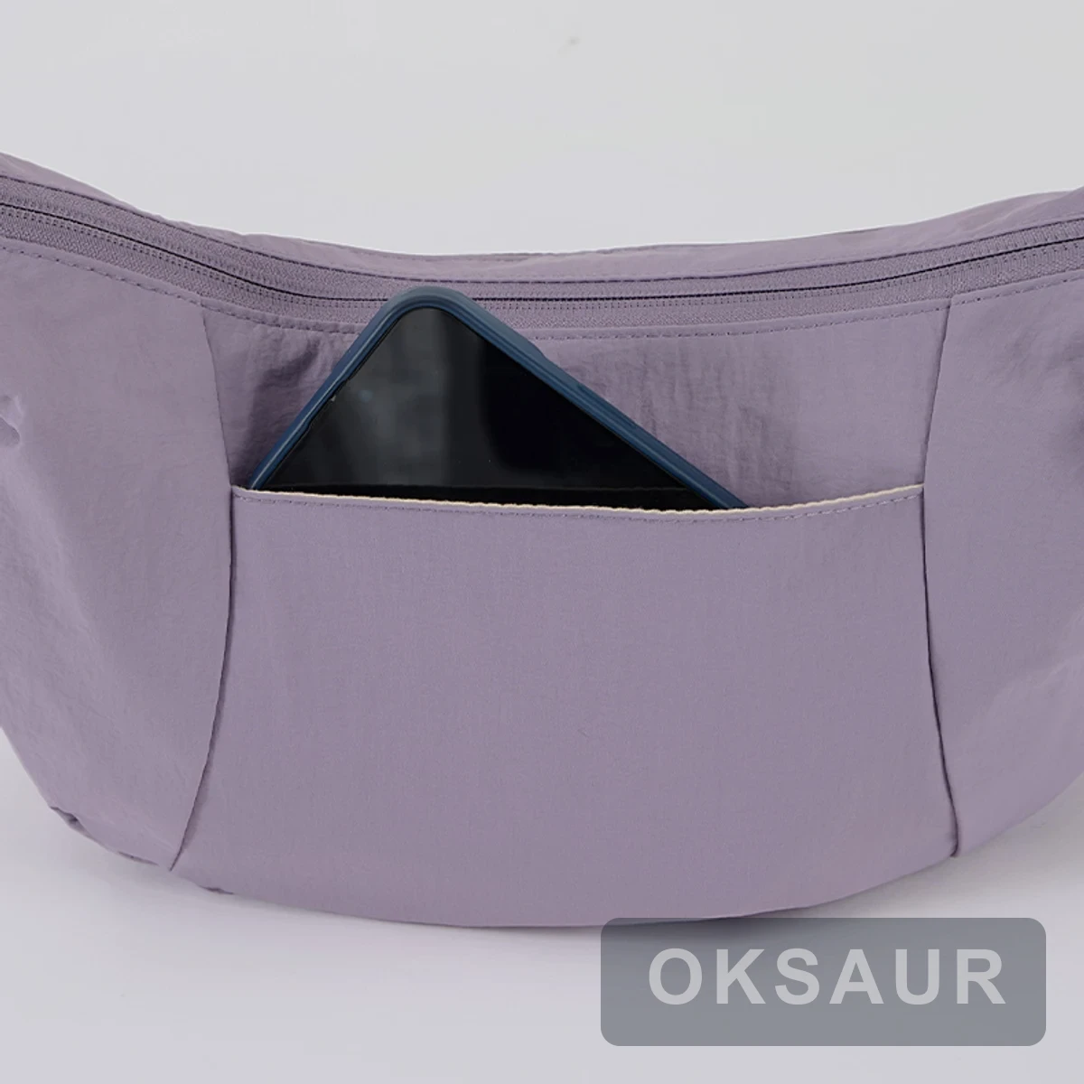 Purple crescent crossbody bag with a phone in its rear slip pocket